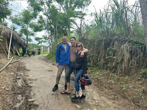       Three people posing on a rural path next to tall grass and trees.
  