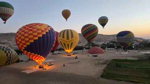 Hot air balloons over a desert landscape during sunrise.