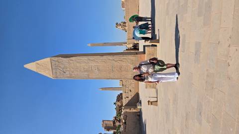 Two people in front of an ancient obelisk with hieroglyphs.