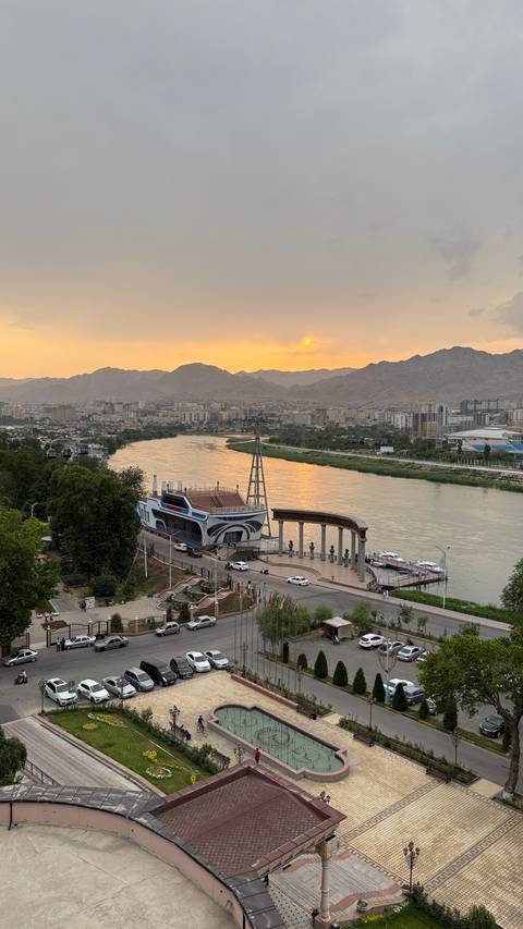 Sunset over a city with river and mountains in the background.