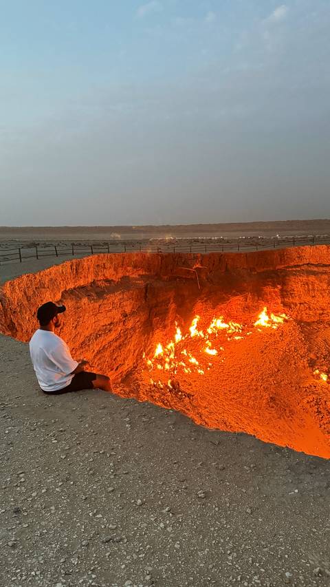       Person sitting on the edge of a fiery crater at night.
  