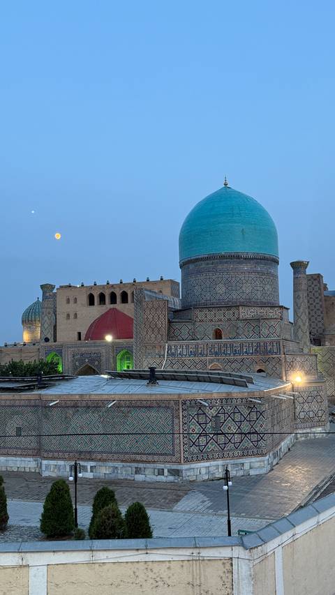       Illuminated complex with domed roofs at dusk.
  