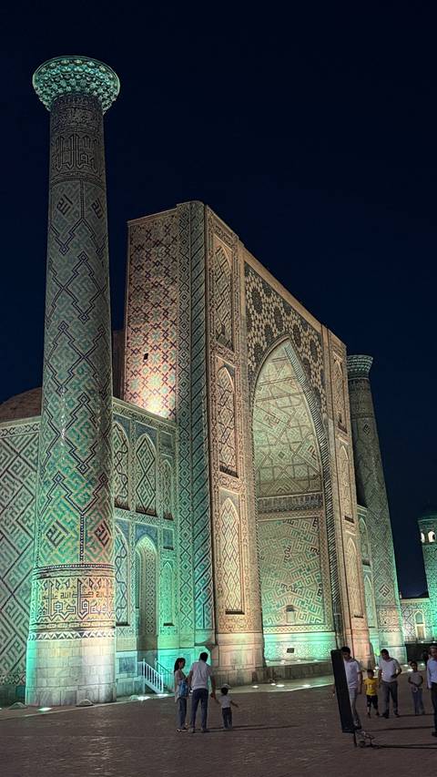       Well-lit historical structure at night with intricate patterns.
  