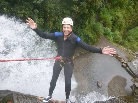       Man abseiling down a waterfall in adventure gear.
  