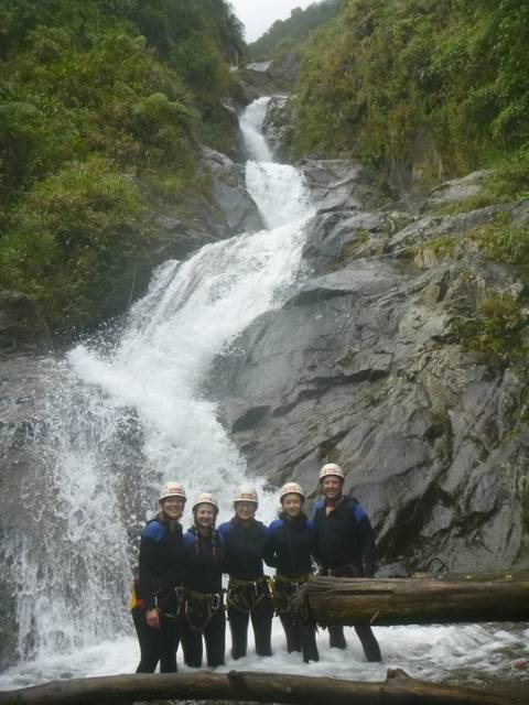       Group of people posing near a waterfall.
  