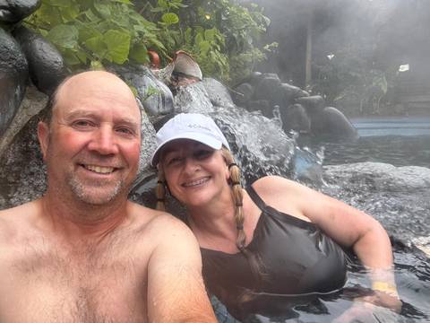       Couple in a hot spring pool with a rock waterfall.
  
