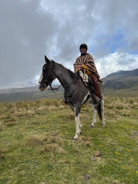       Person in traditional attire riding a horse on a grassy field.
  