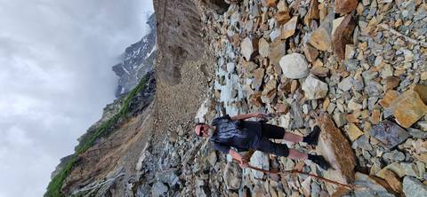 Person standing on rocky terrain with mountains in the background.