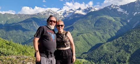 Two people posing with mountains in the background.
