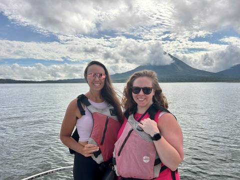 Two women in kayaks with a mountain in the background.