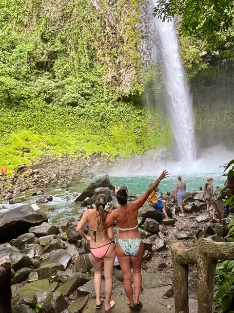People enjoying a waterfall and waving.