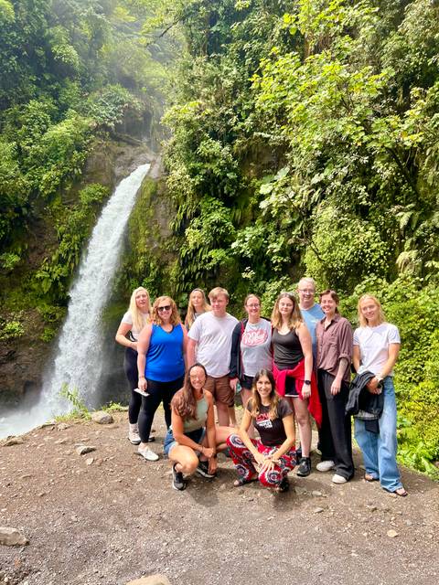 Group posing in front of a waterfall.