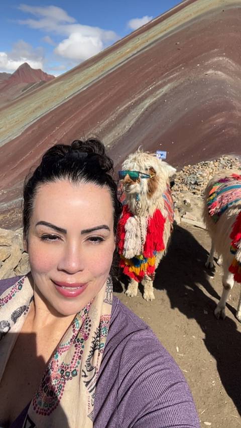 Selfie with a llama wearing traditional decorations.