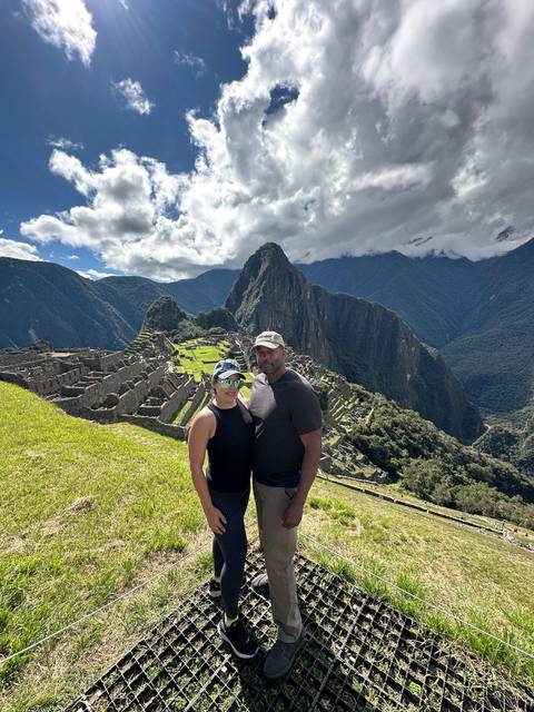 Couple standing in front of Machu Picchu ruins.
