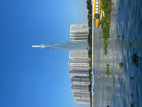       Tall skyscraper beside a river with clear blue skies.
  