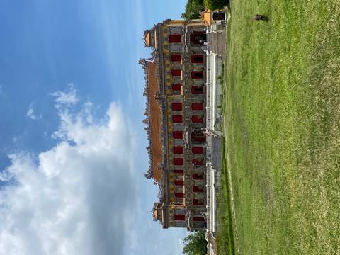       Historical structure with detailed architecture and a grassy foreground.
  