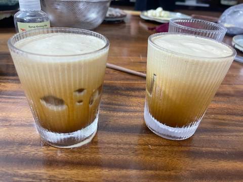 Two glasses of iced coffee on a wooden table.