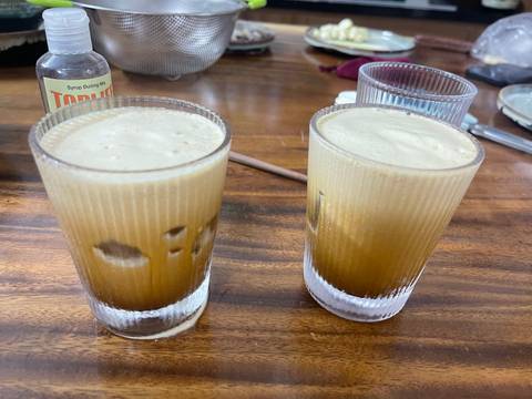 Two glasses of iced coffee on a wooden table.