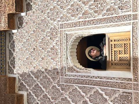       Person looking out from an ornately designed window.
  