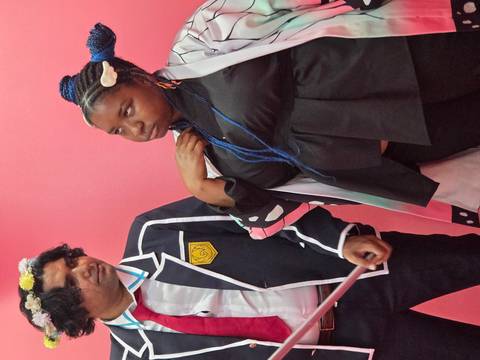       Two people dressed in themed costumes in a pink room.
  