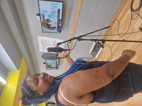       Person in a studio with a microphone and screen.
  