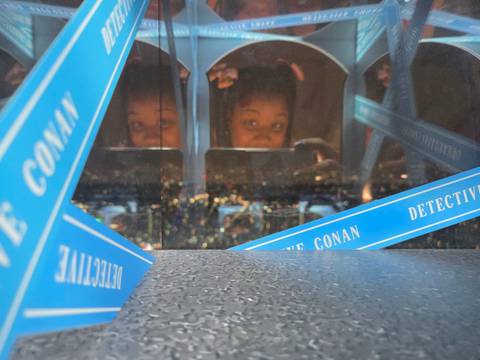 Reflective surface showing person and cityscape images.