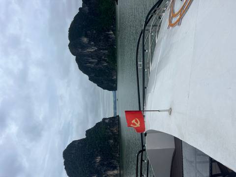      Tour boat with red flag in limestone karst river landscape.
  