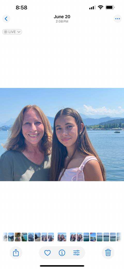 Smiling women posing by a lake with mountains in the background.