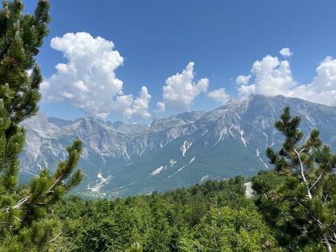       Majestic mountain range with lush greenery and blue sky.
  