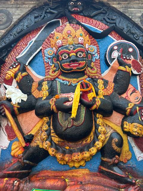       Colorful statue of a deity with multiple arms.
  