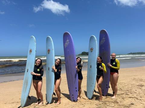Five women holding surfboards on a beach.