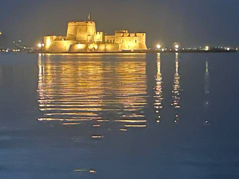 A night view of a well-lit fortress reflecting on water.
