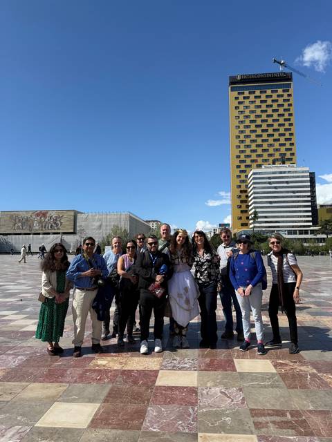 Group photo in a plaza with large modern buildings in the background.