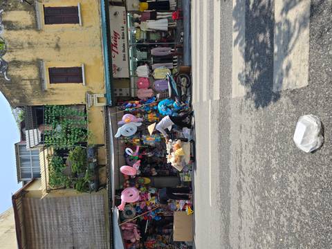       Street view with a shop showcasing various colorful merchandise.
  
