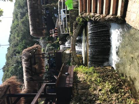       Waterfall with people sitting at a cafe next to it.
  