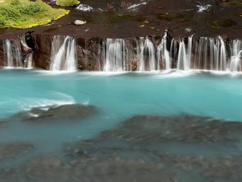 Bright blue waterfalls cascading over dark rocks.
