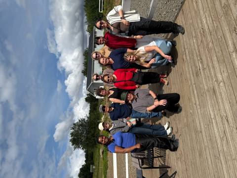       Group of people posing on a wooden platform.
  