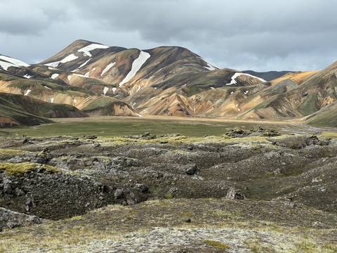       Colorful mountains with patches of snow and green moss.
  