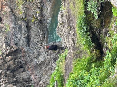       Person standing on rocks near a small water body.
  