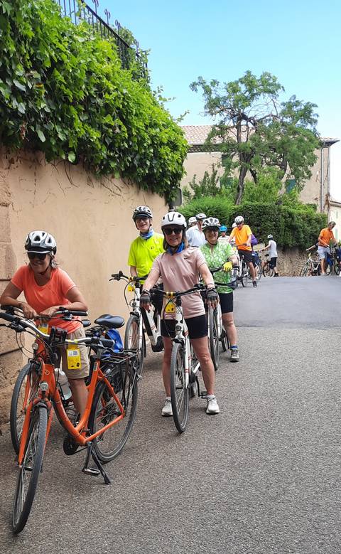 Group of cyclists on a narrow street with bicycles.