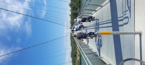 Group of cyclists crossing a suspension bridge.