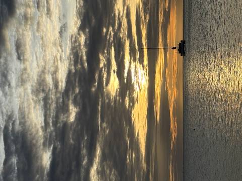       A sailboat during sunset on a body of water.
  