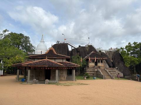 A historic temple complex with a rock backdrop.