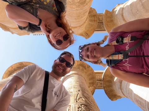       Group of tourists smiling at an ancient Egyptian temple.
  