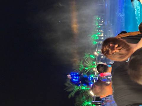 Night scene with people watching a performance with neon lights.