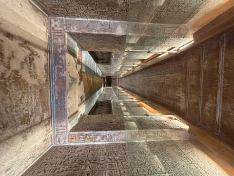 Walkway inside an ancient tomb with carvings.