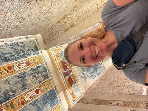 Person inside a tomb with hieroglyphic art.