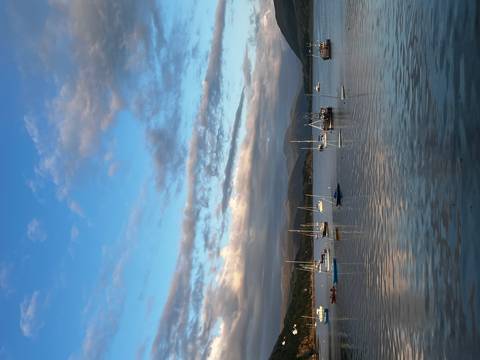 Sailboats on calm water with mountains in the background.