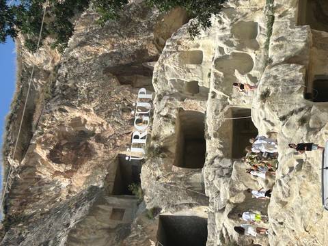       People visiting a rock formation with 'Ürgüp' sign.
  