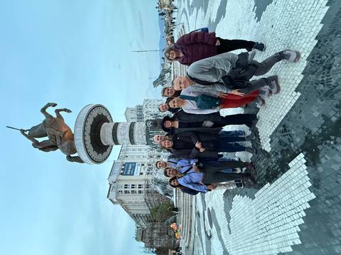 Group of tourists standing in front of a large statue and fountain.